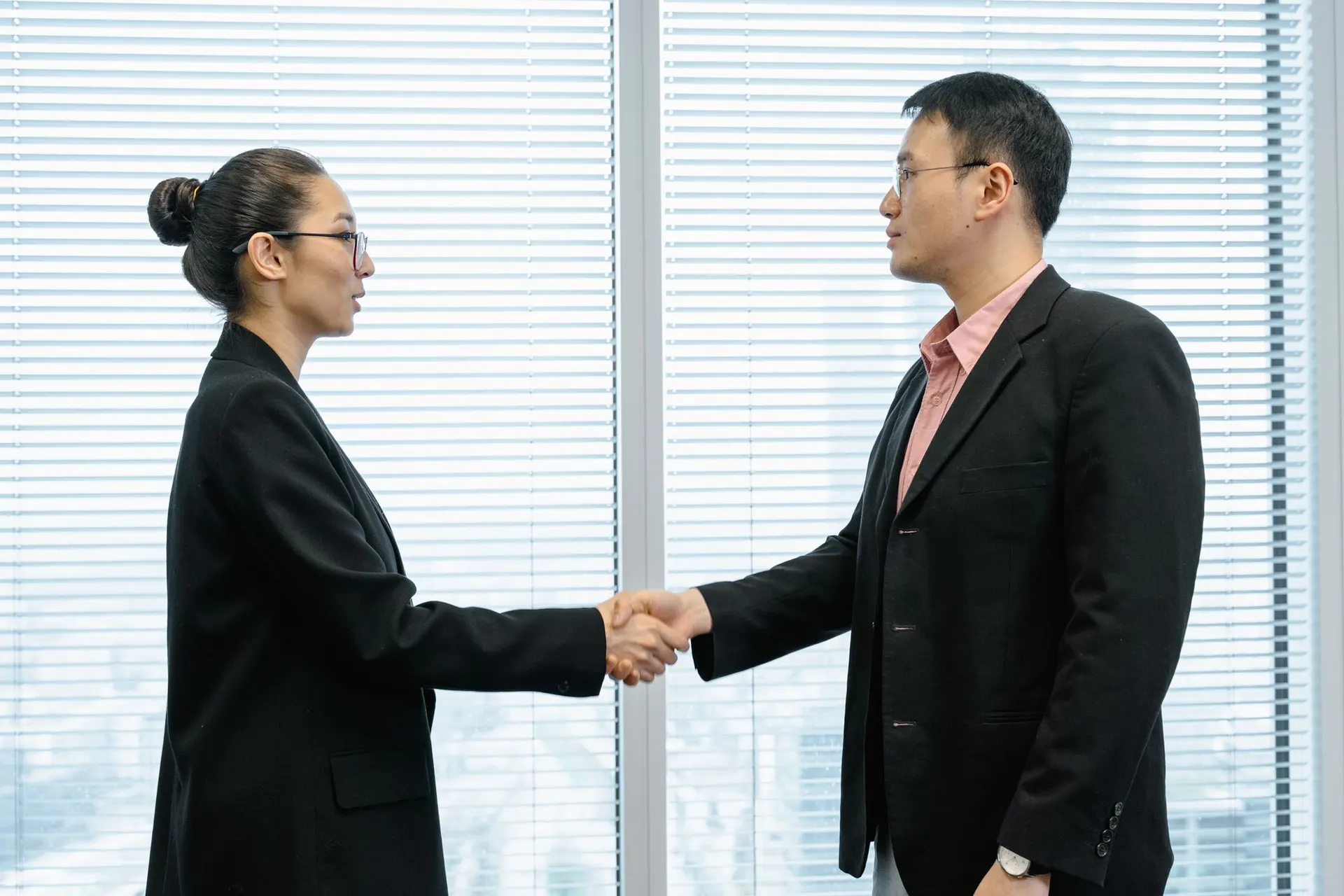 Two colleagues shaking hands in a high-rise office
